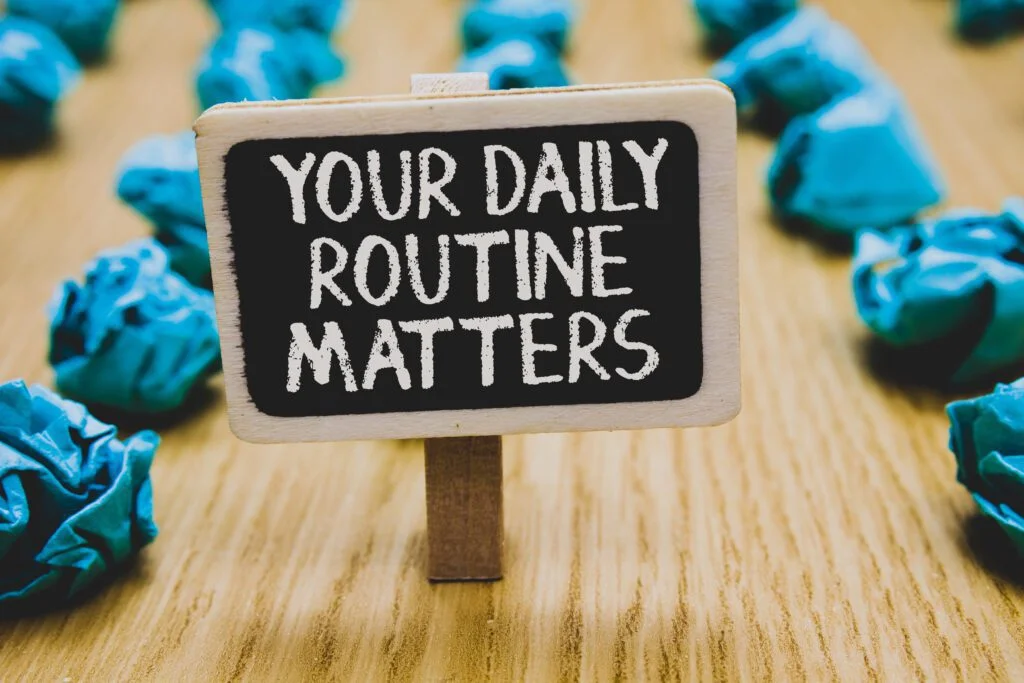 Handwriting text writing Your Daily Routine Matters Concept meaning Have good habits to live a healthy life Stand blackboard with white words behind blurry blue paper lobs woody floor | Chill & Thrive | Chill & Thrive Your Daily Routine Matters