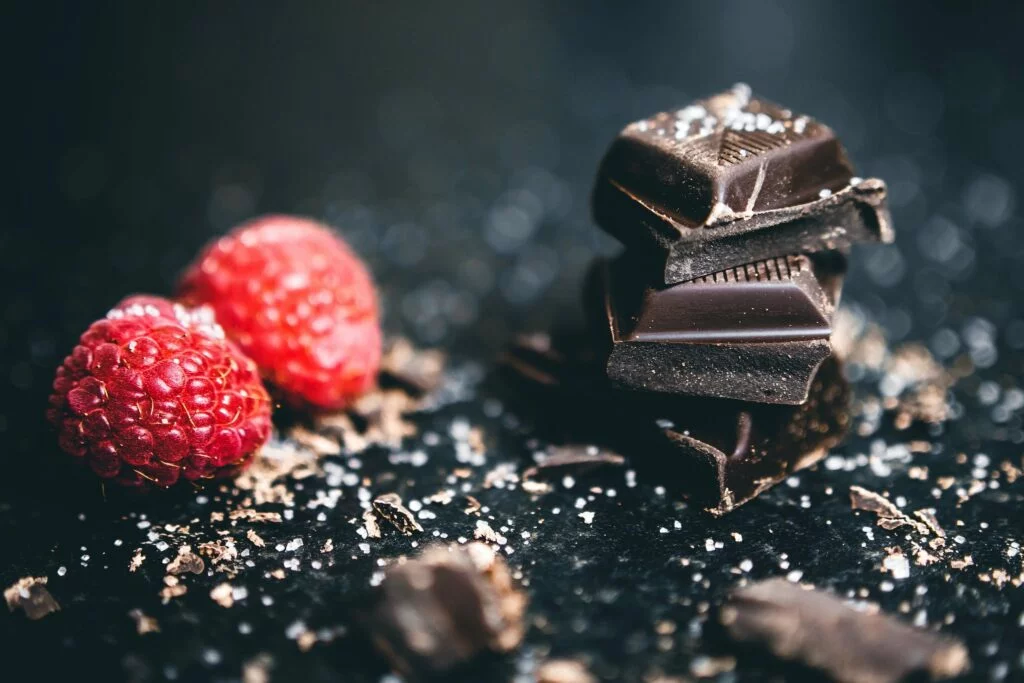 | Chill & Thrive Close-Up Photo Of Stacked Chocolates Bars Beside Raspberries