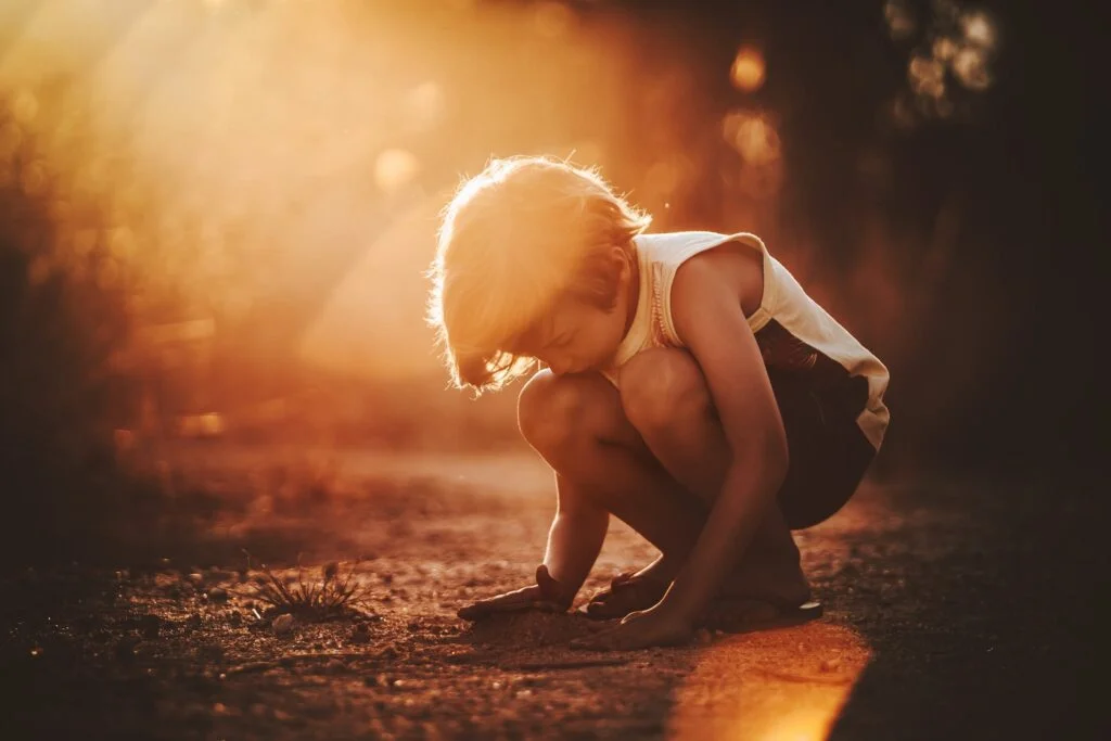 | Chill & Thrive Full body of child in casual clothes squatting and playing with sand in park